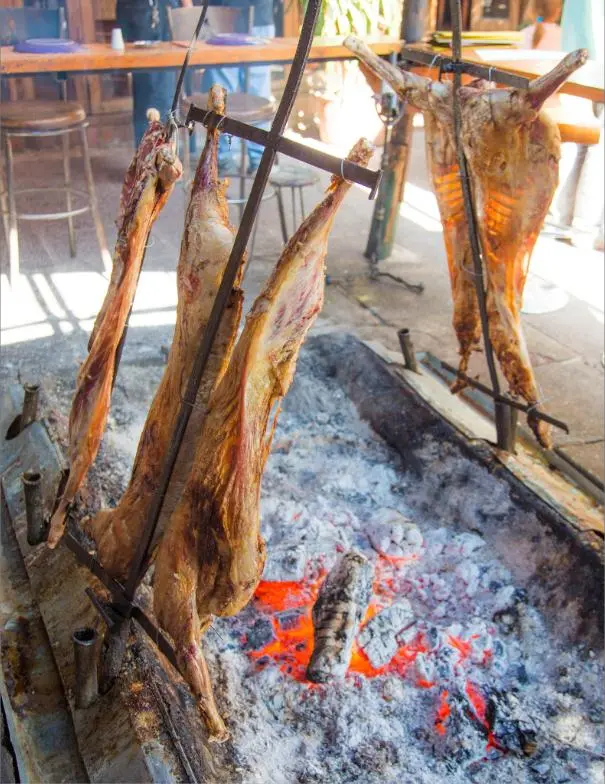 Corderos asándose al palo sobre las brasas